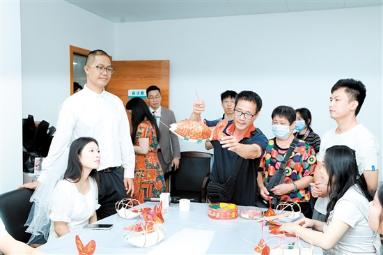 昨日，在新會區(qū)民政局婚姻登記處，工作人員向剛領(lǐng)證的新人們展示新會魚燈制作技巧。