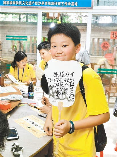 美國華裔青少年李恩誠用茅龍筆在扇面上寫下唐詩。