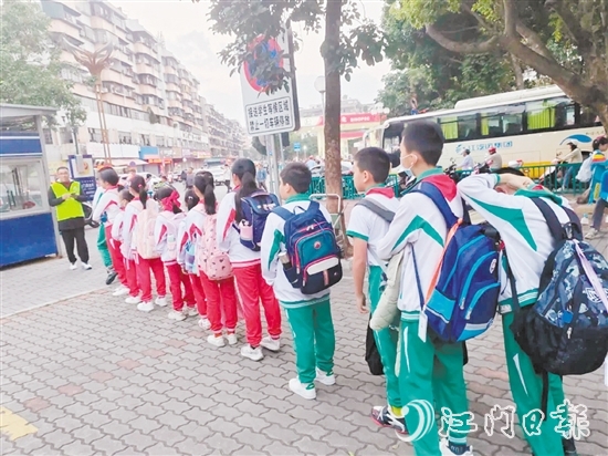新會圭峰小學(xué)的學(xué)生有序排隊，準(zhǔn)備搭乘校園定制公交專線。