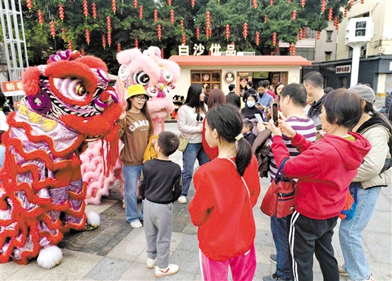 游客在長(zhǎng)堤歷史文化街區(qū)與醒獅合影。何雯意