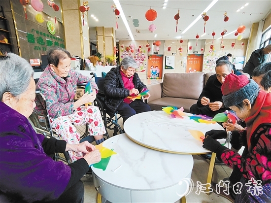 老人們圍坐在桌前，專注地制作小風(fēng)車。