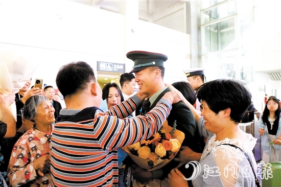 身著軍裝的返鄉(xiāng)退役士兵逐一出站，迎接他們的是鮮花與擁抱。