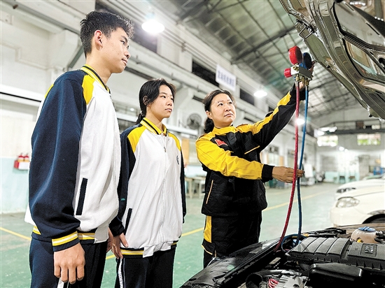 黃錚（右一）在汽修實(shí)訓(xùn)車間指導(dǎo)學(xué)生。