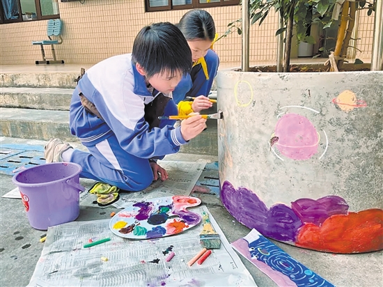 學(xué)生們在校園內(nèi)的花墩上進(jìn)行精心繪制，為校園風(fēng)景增色添彩。