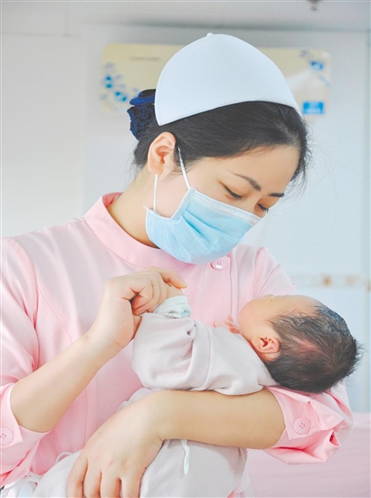 這是一雙托起生命的手。江門市中心醫(yī)院愛嬰?yún)^(qū)主管護(hù)師湯玲玲正在安撫哭鬧的寶寶。她一手環(huán)住襁褓，一手牽起寶寶的小手，動作舒緩而溫柔。在這里，生命的啼哭與溫柔的守護(hù)相遇，匯聚成世間至暖的力量。（林錦棠