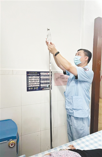 吳益浩核對(duì)藥液、為患者調(diào)整輸液流速。