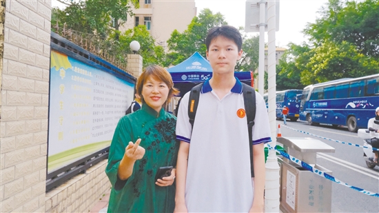 身著綠色旗袍的李女士與兒子合影。