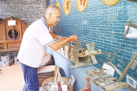 新華村打造農(nóng)耕文化展館，留住鄉(xiāng)村記憶。圖為村中老人向記者介紹農(nóng)具。