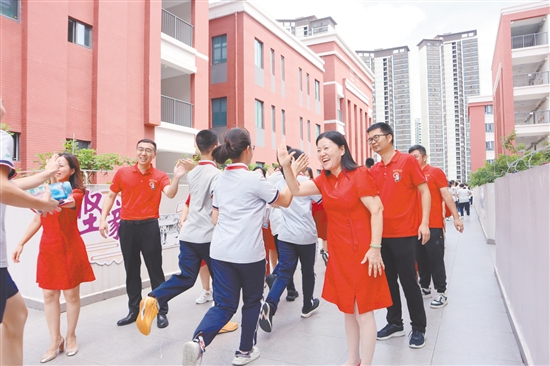 蓬江區(qū)紫茶中學(xué)的領(lǐng)導(dǎo)和老師們與考生們擊掌，為他們加油、鼓勁。