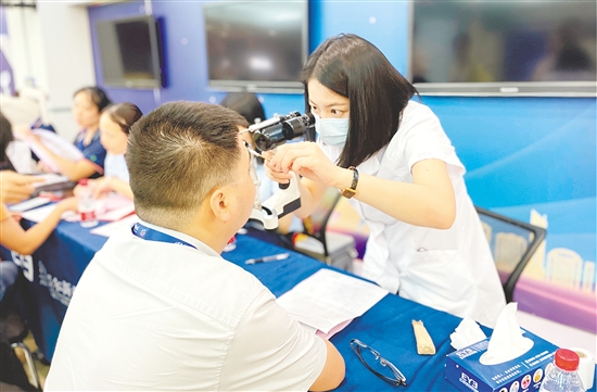 醫(yī)護(hù)人員為企業(yè)職工檢查眼睛。