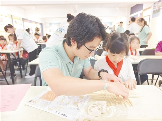 學(xué)生志愿者耐心教導(dǎo)孩子制作手工。