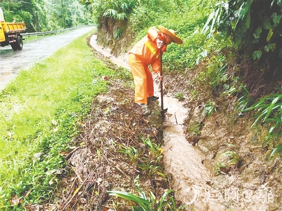 道路養(yǎng)護(hù)人員清理被泥沙落葉堵塞的邊溝涵洞，確保雨水快速排走。