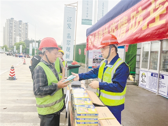 工地施工人員排隊領(lǐng)取防蚊用品。